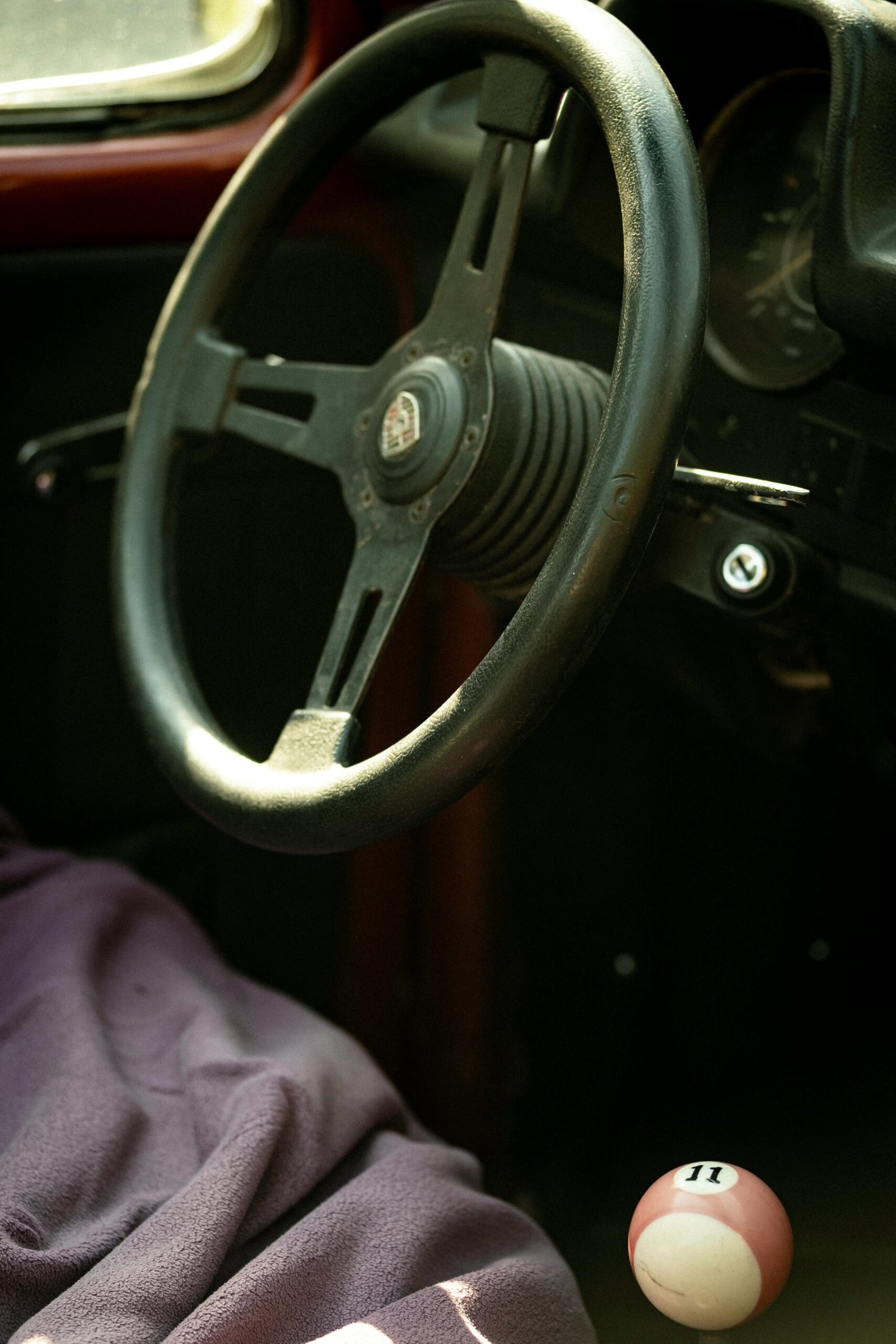 Close-up of a vintage car's steering wheel and gear shift in a classic convertible.